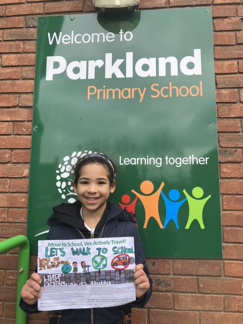 Photo of girl from Parkland Primary School holding up a poster she designed to encourage active travel to school.